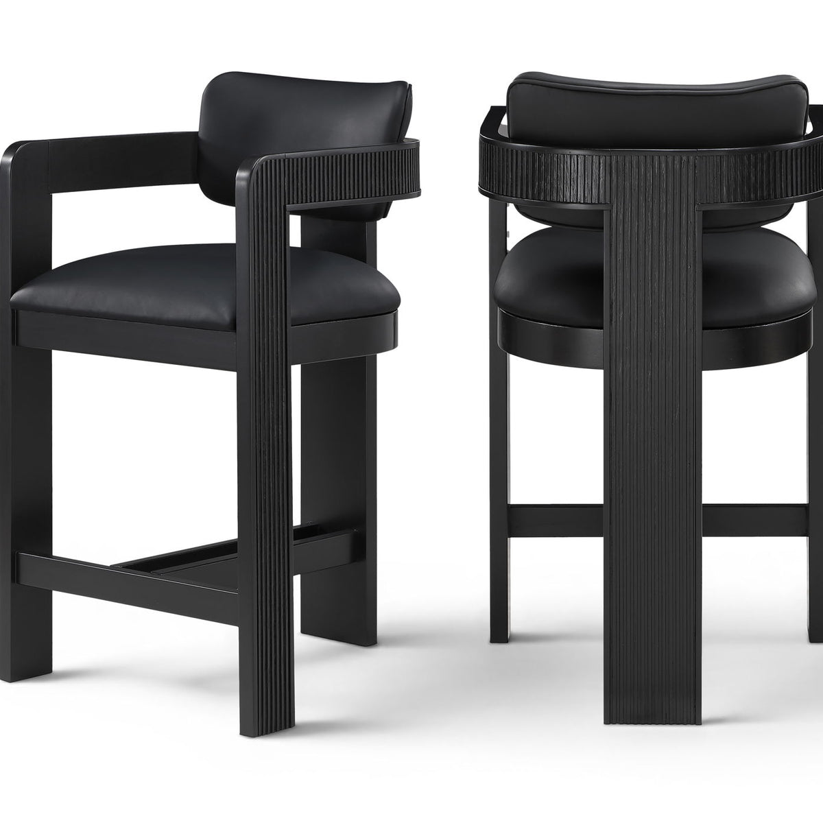 Two vegan leather counter stools with black upholstered seats and black ribbed frames