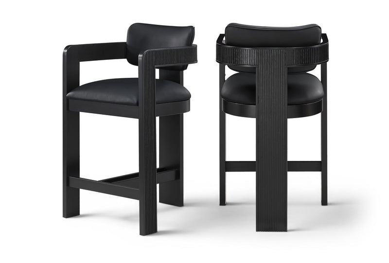 Two vegan leather counter stools with black upholstered seats and black ribbed frames
