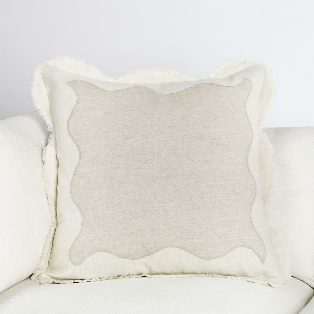 Tollo beige linen square pillow on sofa with scalloped edges and textured weave
