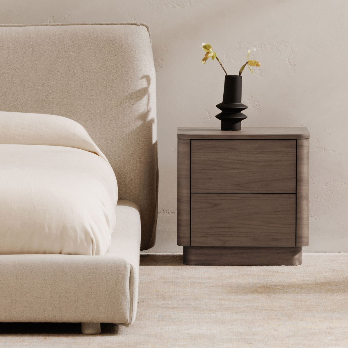 Walnut two-drawer nightstand with smooth top, dark trim, and rounded legs.