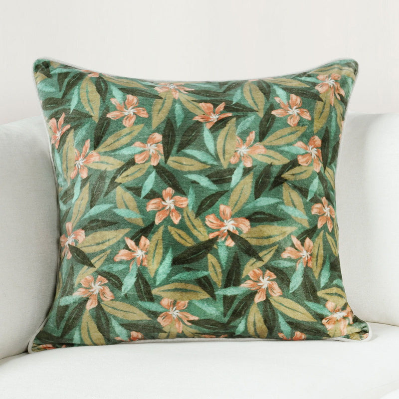 Green tropical floral decorative pillow with light piping and orange blossoms.