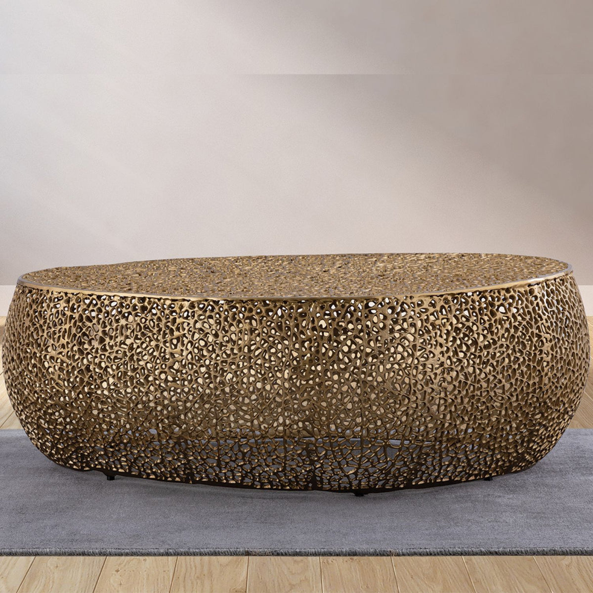 Gold oval coffee table with textured mosaic pattern and low rounded base, angled view