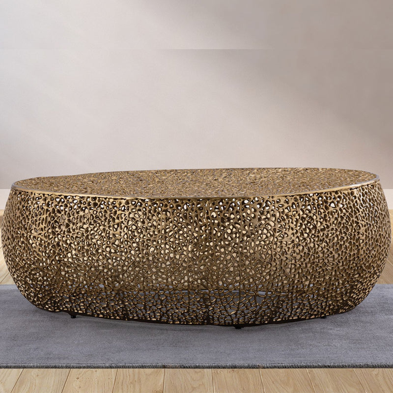 Gold oval coffee table with textured mosaic pattern and low rounded base, angled view