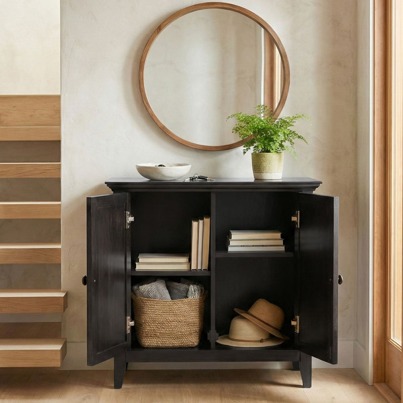 Dark low storage cabinet with two doors open, revealing shelves and interior items