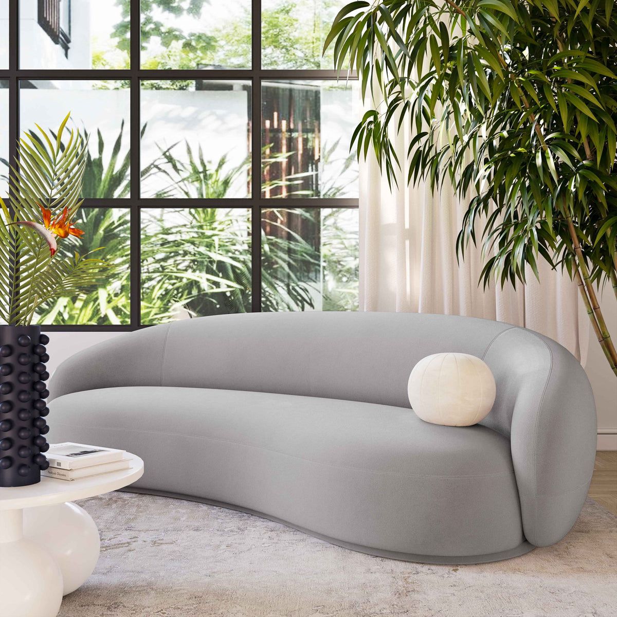 Gray velvet sofa with rounded back and white round accent pillow