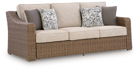 Beige cushion sofa with woven wicker arms and two patterned throw pillows
