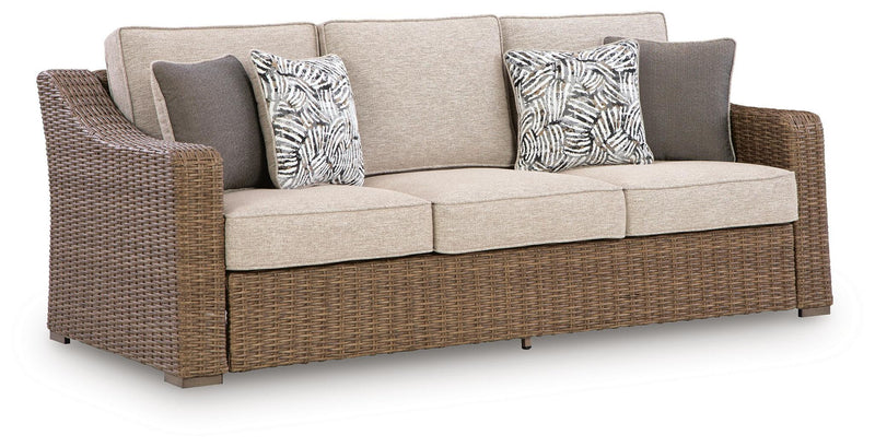 Beige cushion sofa with woven wicker arms and two patterned throw pillows