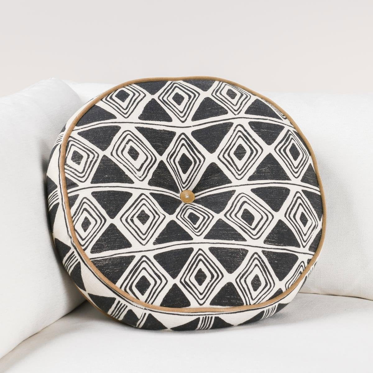 Black and white geometric patterned square pillow on sofa, tan piping detail