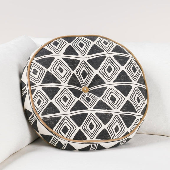 Black and white geometric patterned square pillow on sofa, tan piping detail