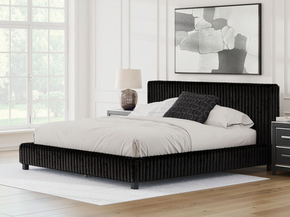 Black upholstered bed with white bedding and two pillows, ribbed headboard
