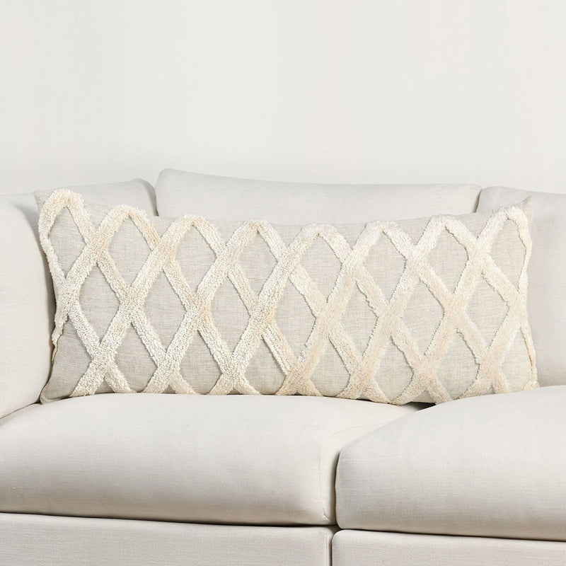 Natural ivory lumbar pillow on sofa with raised diamond embroidery and fringed borders