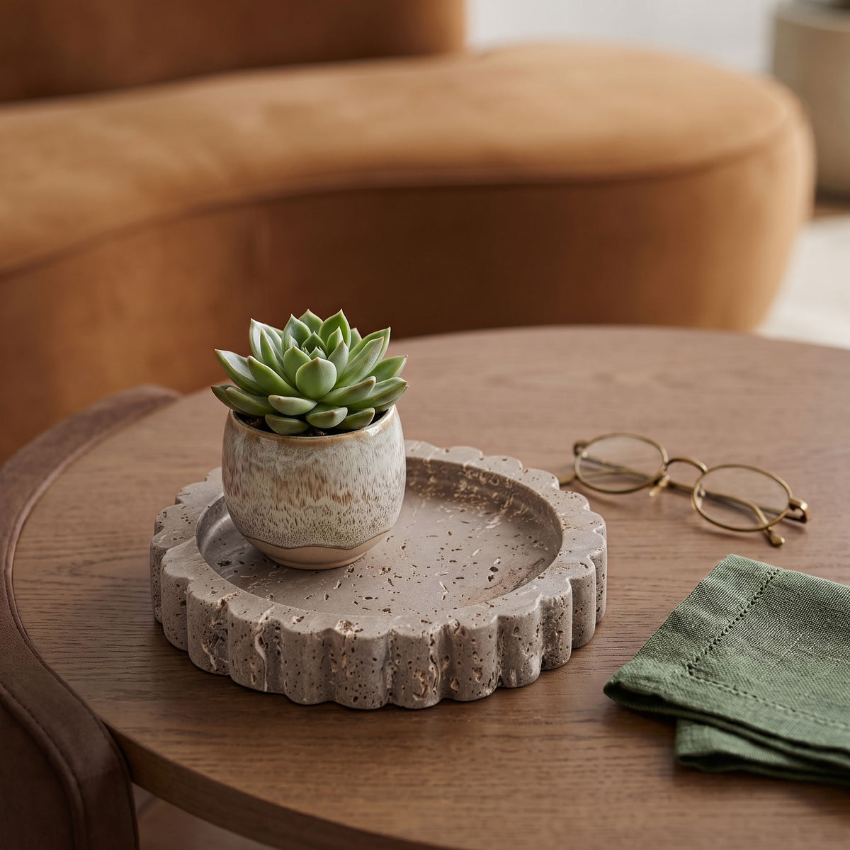 Beige travertine serving tray with scalloped rim centered on a wooden table