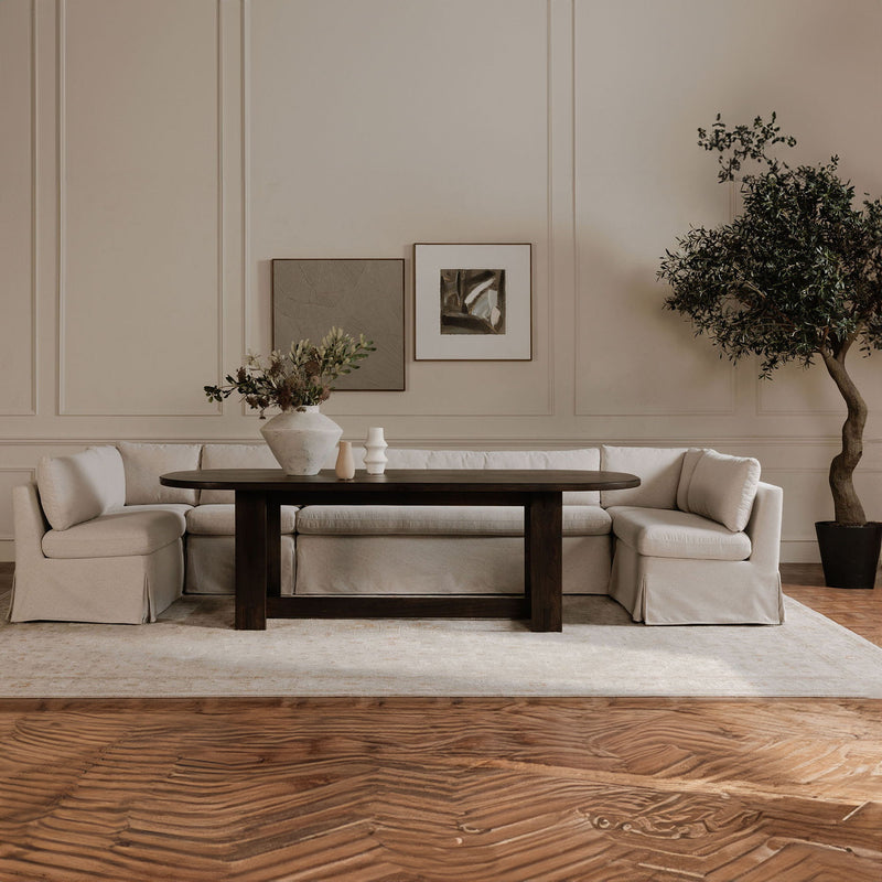Beige slipcovered slipper chair with wide arms and padded seat, angled view