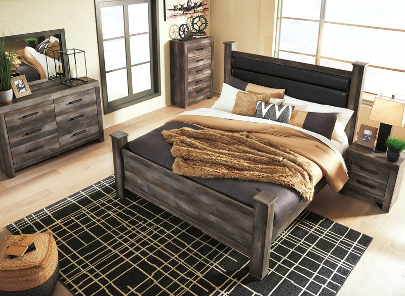 Gray upholstered poster bed with tall headboard and footboard, styled with bedding set