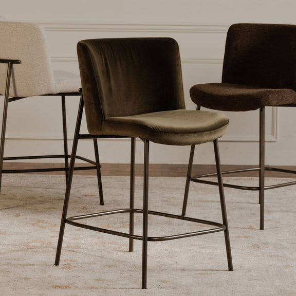 Green upholstered bar stool with curved back, cushioned seat, metal footrest frame