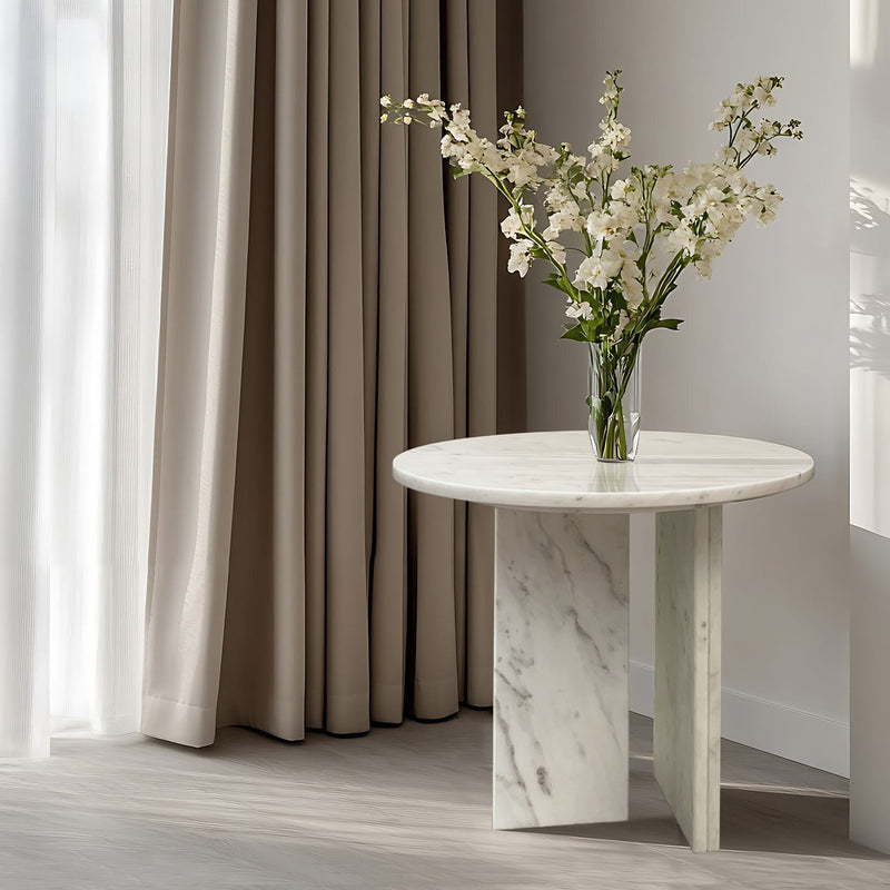 Round white marble coffee table with veined stone pedestal and tabletop base.