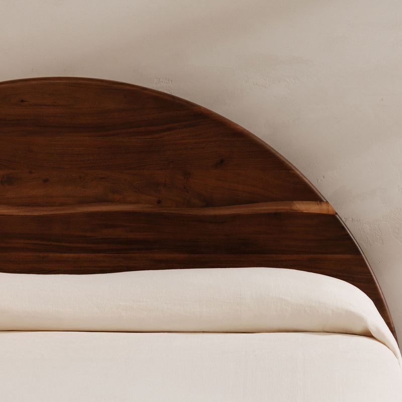Close-up of brown arched headboard with wood grain panels and curved top