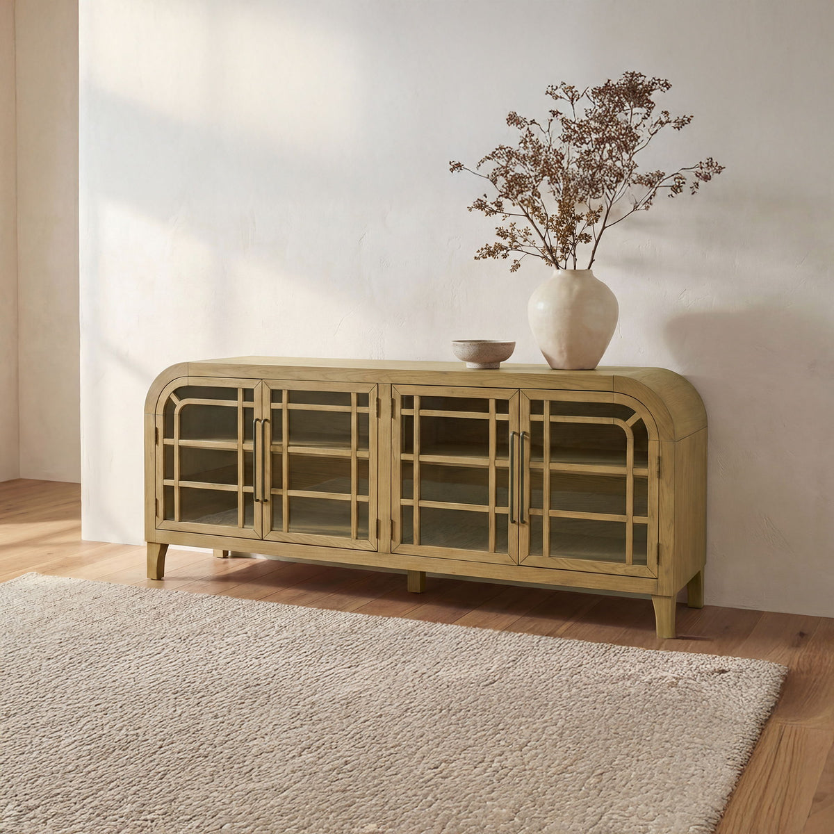 Natural wood sideboard with glass doors and curved front, standing on legs.
