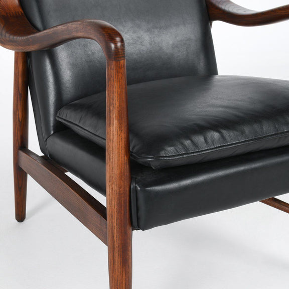Kiannah club chair close-up: dark leather-look seat cushion with walnut arm and base