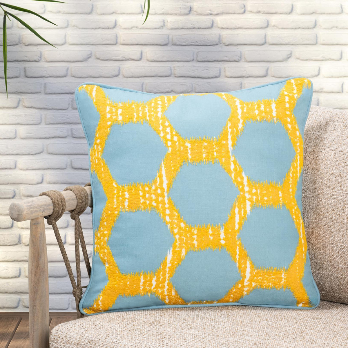 Blue decorative pillow with yellow lattice geometric design and piped border