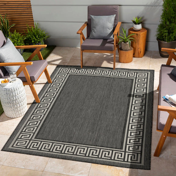 Outdoor-ready dark gray area rug with light Greek key trim and central panel.