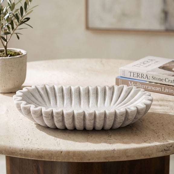 Decorative round bowl with vertical ridges, light gray finish on tabletop.