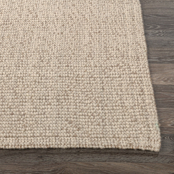 Natural speckled woven rug corner with short pile edge detail