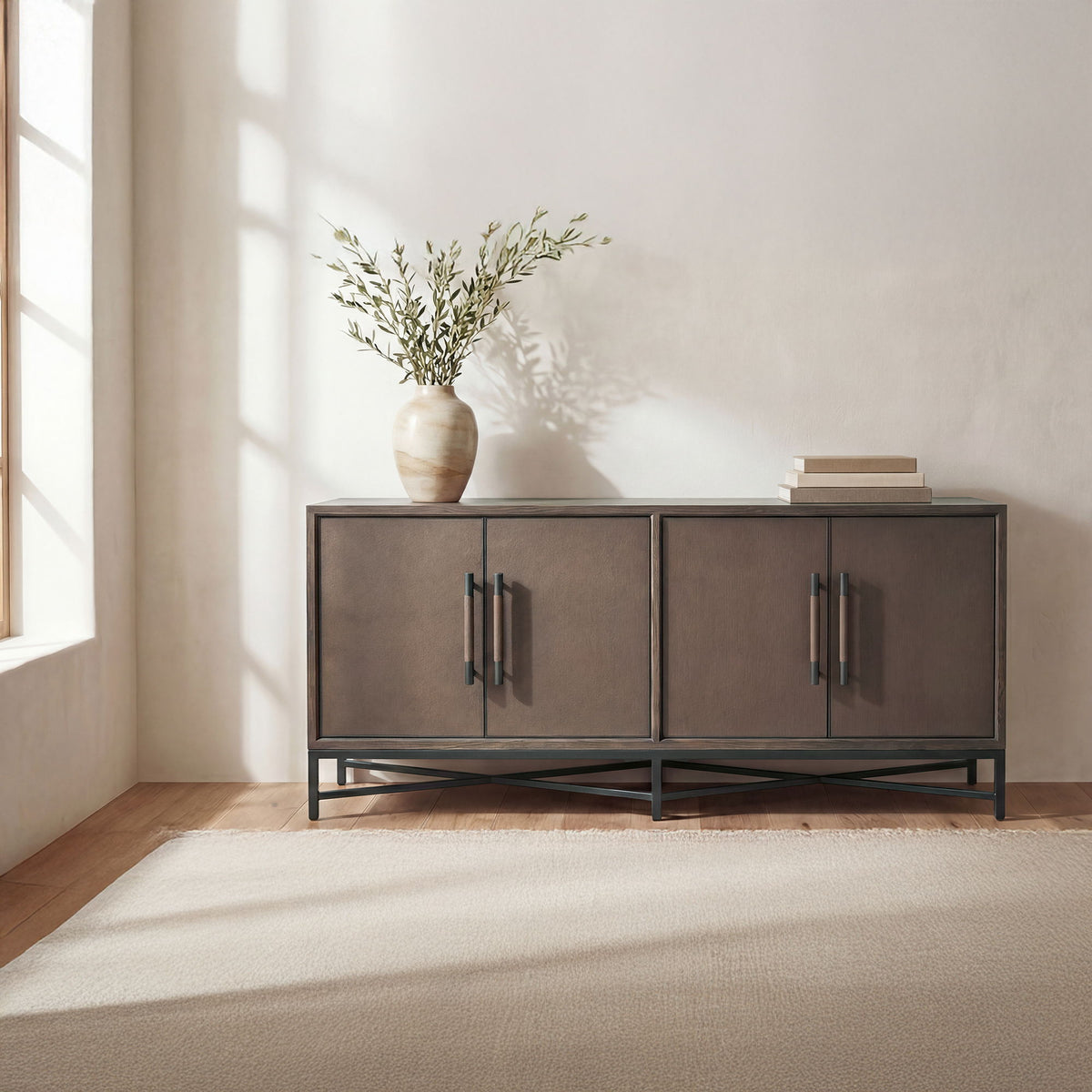 Brown sideboard with four cabinet doors and metal bar handles, raised black legs