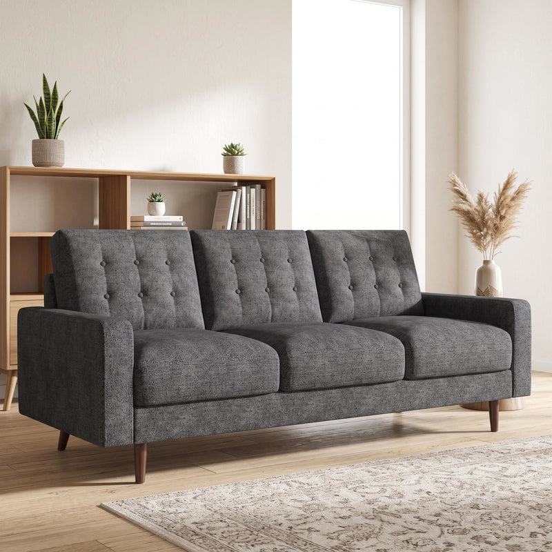 Three-seat sofa in dark gray upholstery with tufted back, wide arms, and tapered wood legs