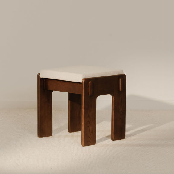 Counter stool with light beige seat cushion and dark brown wood frame with vertical accents