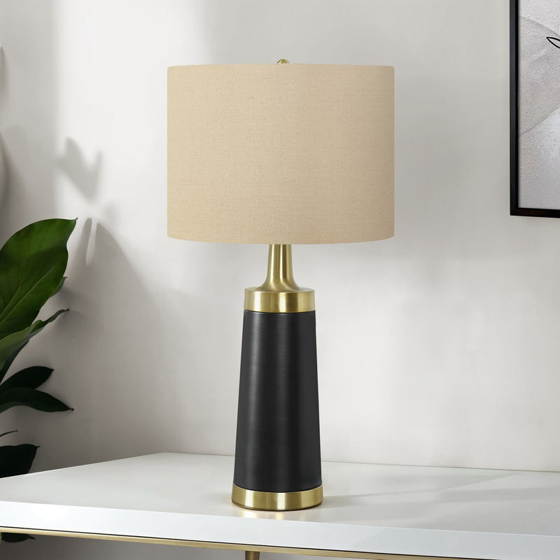 Table lamp with cream fabric shade, black resin body, and gold base; modern silhouette