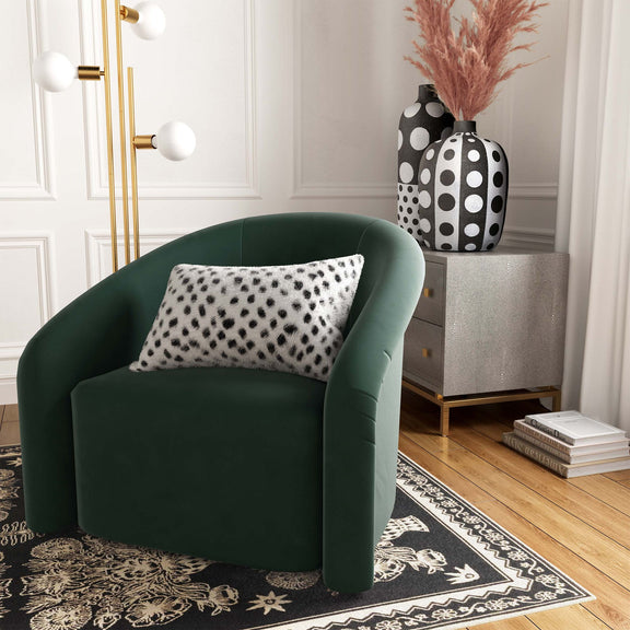 White and black spotted lumbar pillow on green armchair, plush fur