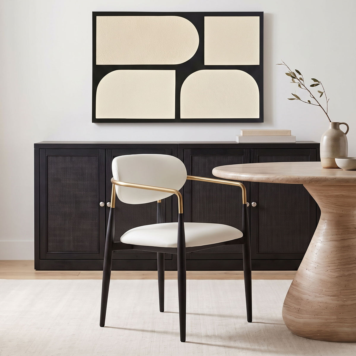 White upholstered dining arm chair with rounded back, black legs, gold arm frame