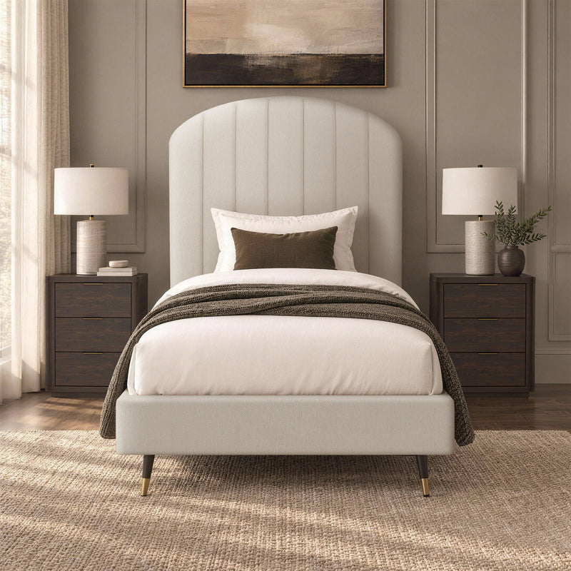Beige arched upholstered bed with white comforter and dark striped throw