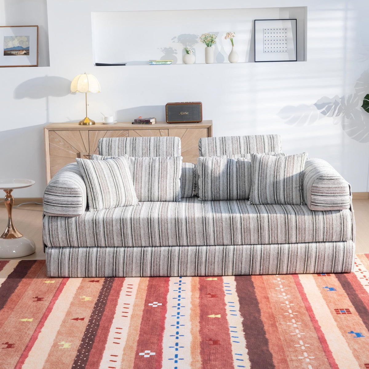 Striped sleeper sofa bed with rolled arms and back pillows in living room