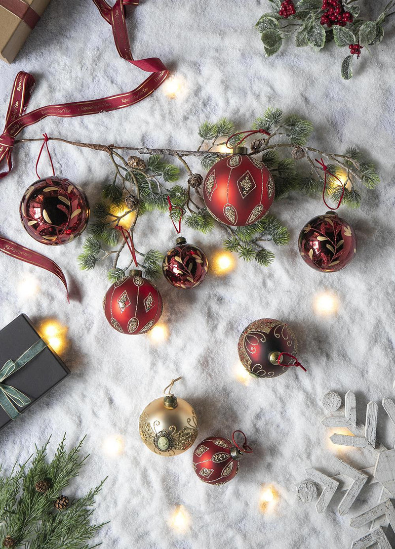 Red and gold hanging Christmas ball ornaments scattered on white snow with lights