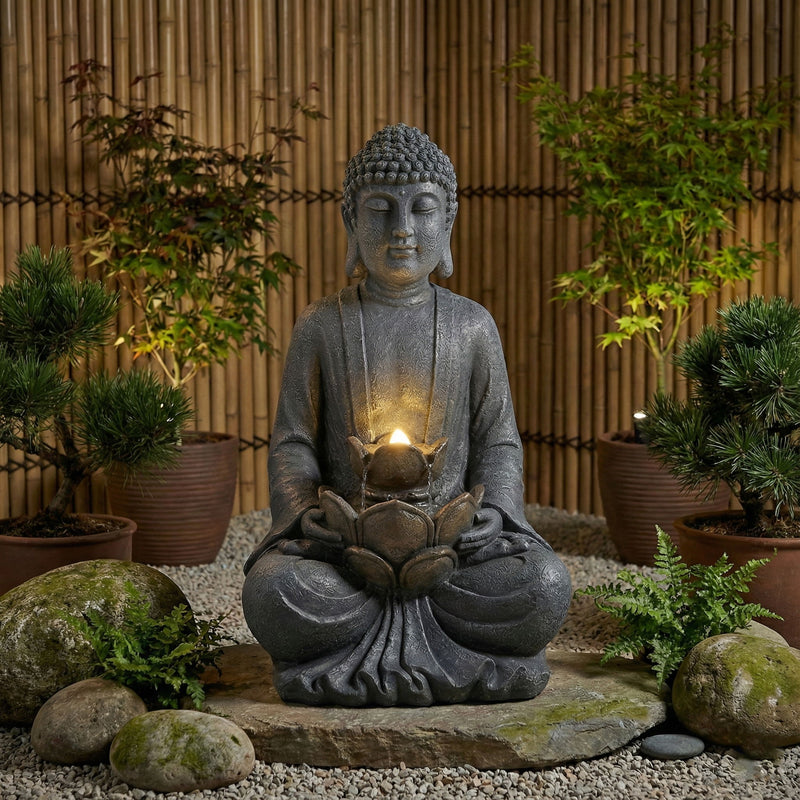 Gray seated Buddha water fountain with glowing bowl and LED light, garden scene