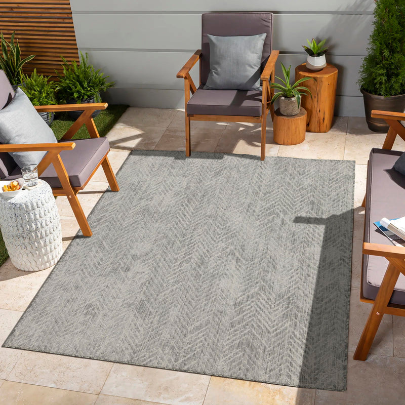 Gray indoor/outdoor area rug with light zigzag chevron pattern and textured flat weave.
