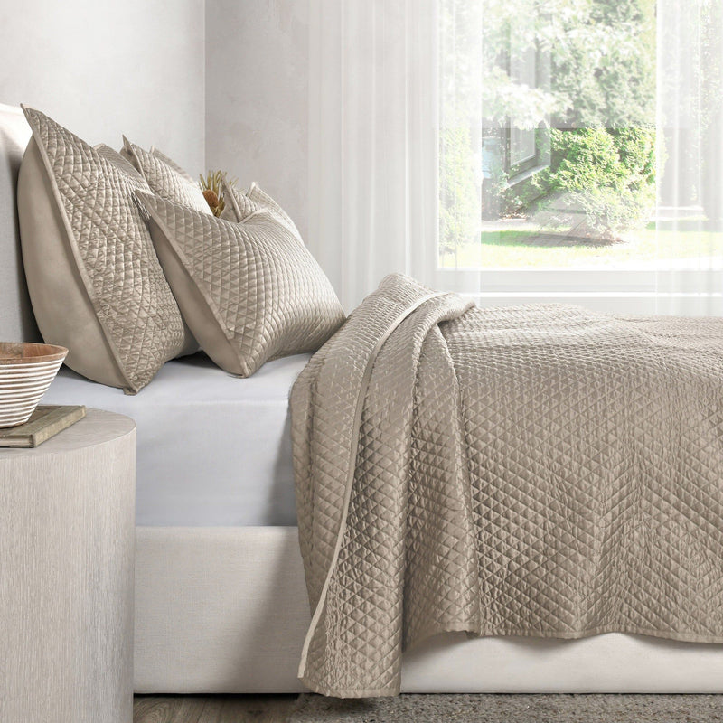 Diamond-quilted taupe pillow shams on a sofa, matching quilted fabric and texture