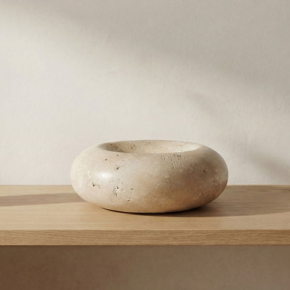 Oval beige stone catchall bowl on wooden surface, smooth with speckled finish