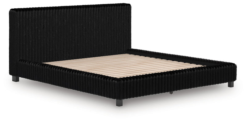 Black upholstered bed frame with ribbed sides and beige mattress, low profile