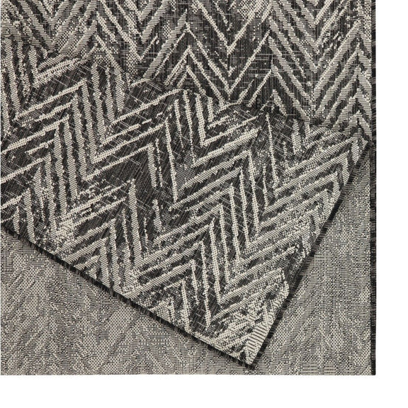 Indoor/outdoor area rug close-up: dark gray and cream chevron pattern along folded edge.