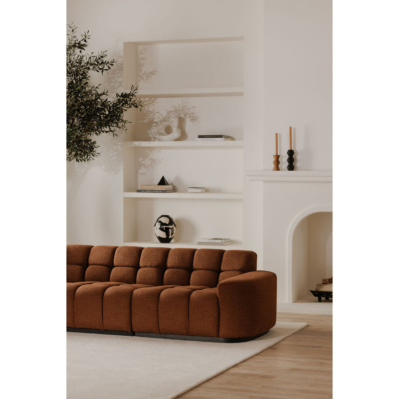 Rust-brown L-shaped sectional sofa with rounded side, tufted back, and ottoman-style seat