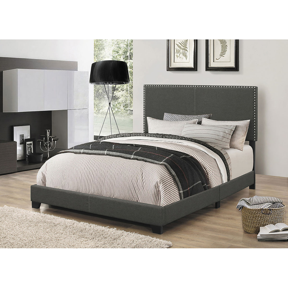 Dark gray upholstered bed with nailhead-trimmed headboard and 2 throw pillows