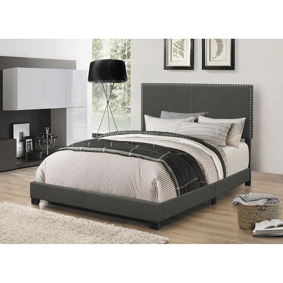 Dark gray upholstered bed with nailhead-trimmed headboard and 2 throw pillows