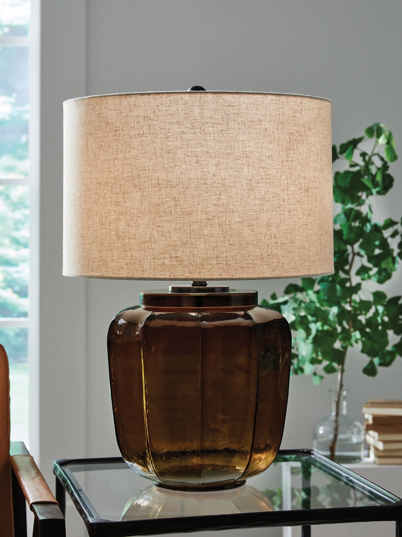 Amber glass table lamp with fabric drum shade on clear glass table