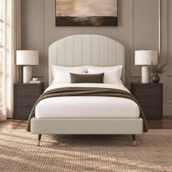 Beige arched upholstered bed with white bedding and dark throw blanket