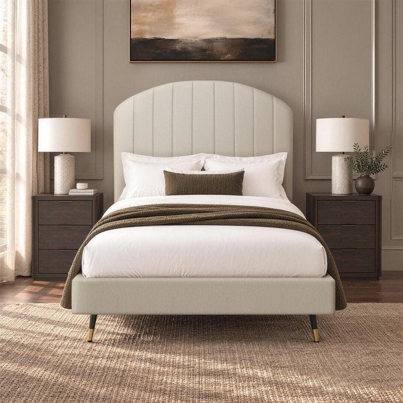 Beige arched upholstered bed with white bedding and dark throw blanket