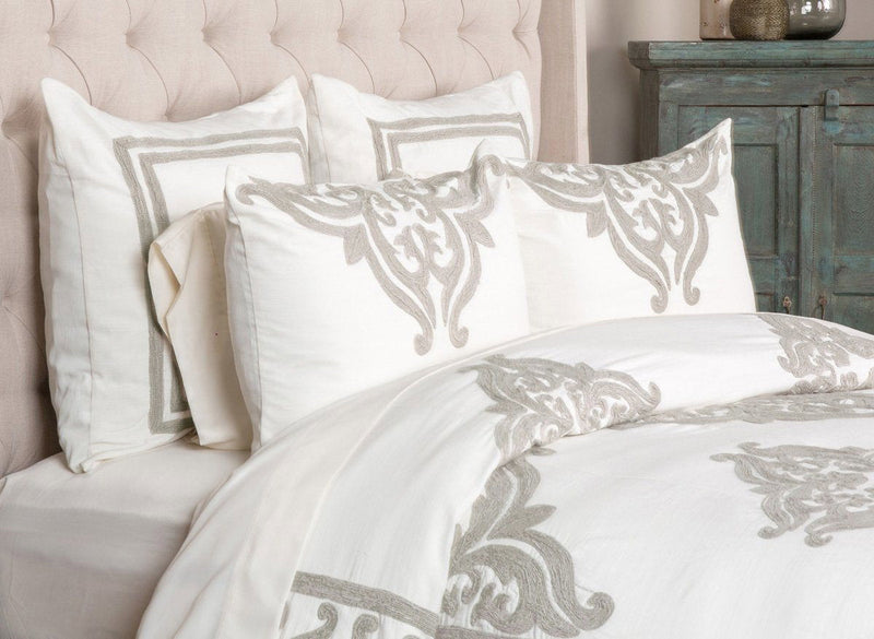 Ivory sham pillow with gray damask crest embroidery, styled with matching bedding