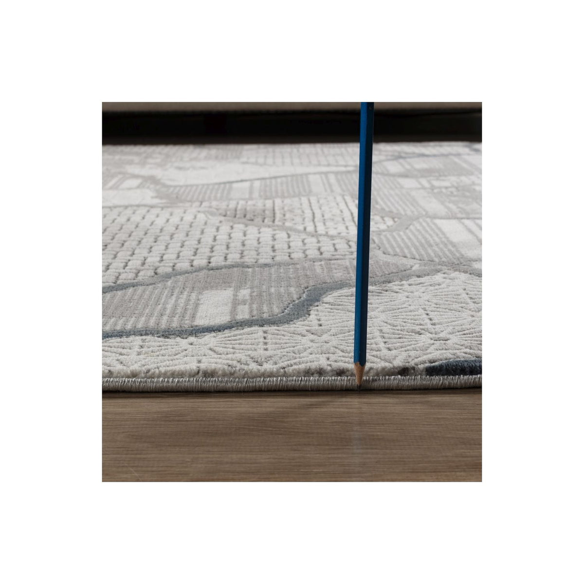 Gray area rug close-up with raised weave and blue-bordered motif along edge